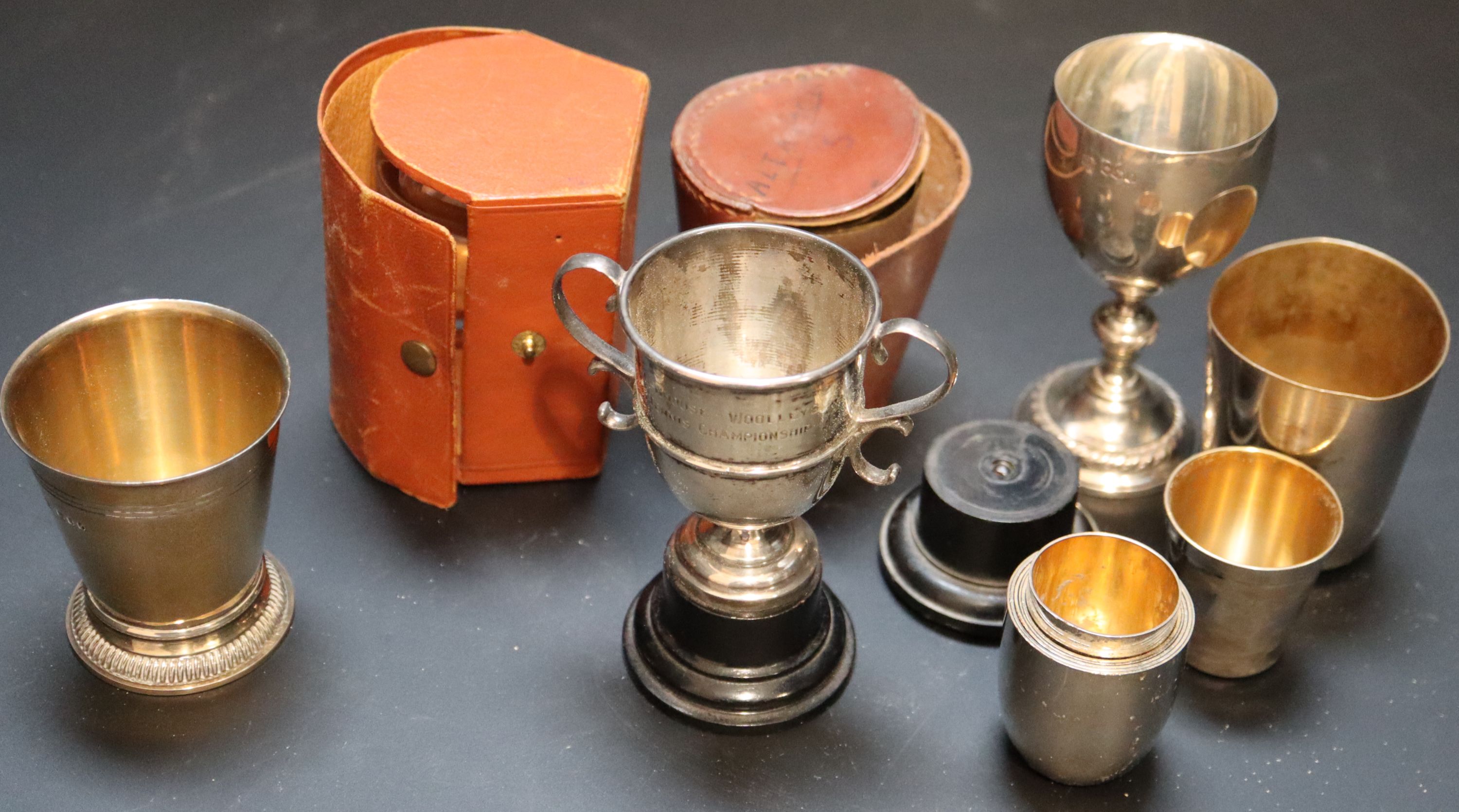 Two small silver trophy cups, largest 97mm, a modern silver gilt beaker and a group of assorted plated travelling beakers.